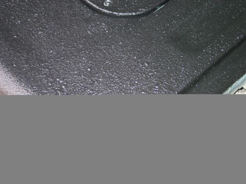 1989 Ford Bronco - Close-up of a black textured tailgate, possibly from a Ford Bronco, with white speckles and a Supermotors.net watermark.