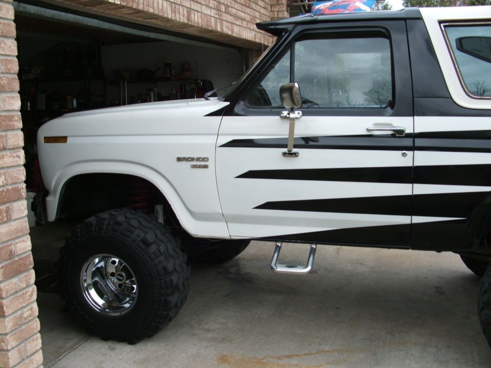 White and black 1985 Ford Bronco with large tires and custom graphics