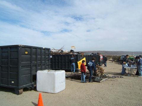 1988 Ford Bronco - People participate in a cleanup event in a desert landscape, with large dumpsters for waste collection.