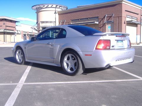 2003 Ford Mustang - This silver 2003 Ford Mustang GT coupe is shown from the rear 3/4 angle, highlighting its spoiler and GT badging.