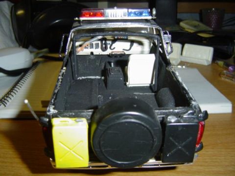 1979 Ford Bronco - Model police SUV with spare tire, jerry cans, and light bar is shown from the rear.