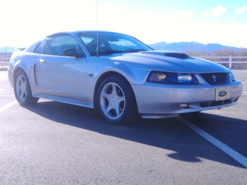 2003 Ford Mustang - A silver 2003 Ford Mustang GT is parked on asphalt with mountains in the background.