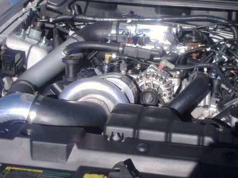 2003 Ford Mustang - Close-up view of an engine bay a turbocharger and custom intake piping.