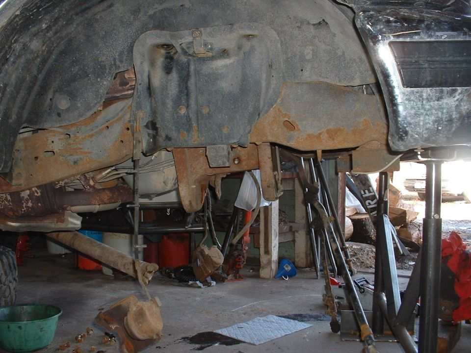 1993 Ford Bronco undercarriage, heavily rusted frame and suspension components, lifted on jack stands