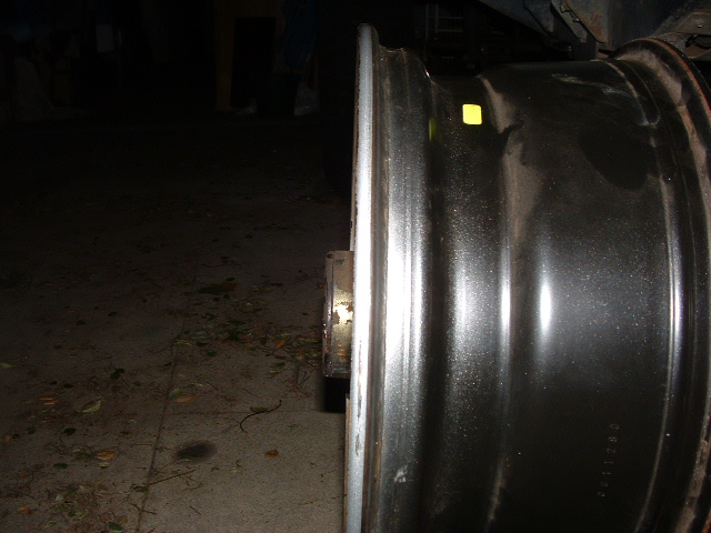 Close-up of a metallic wheel rim with a yellow sticker and some faint markings