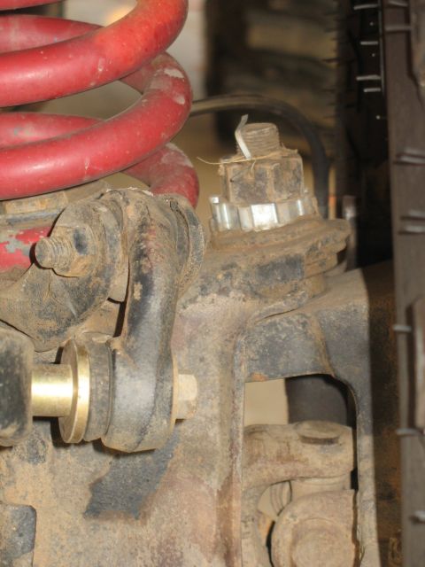 1987 Ford Bronco - Suspension part detail, including a red coil spring and various metal fasteners and brackets.
