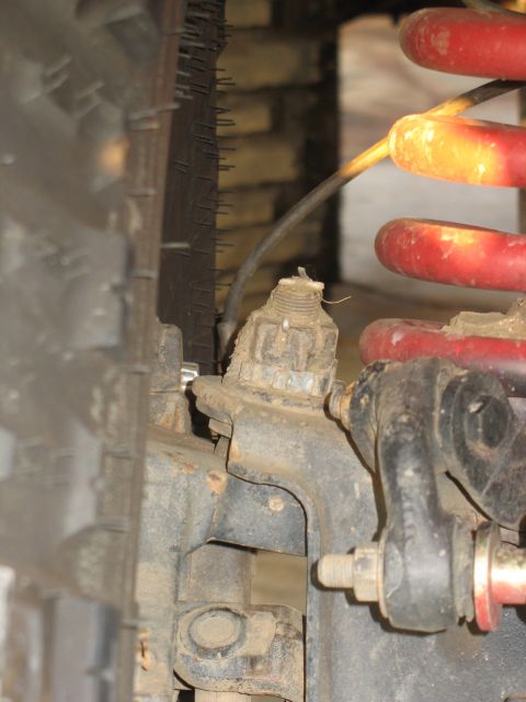 1987 Ford Bronco - Detail of a vehicle's suspension system, showing a tire, coil spring, and various mechanical components.