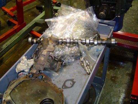 1979 Ford Bronco - Engine parts, including a camshaft, are organized on a cart for a rebuild project.