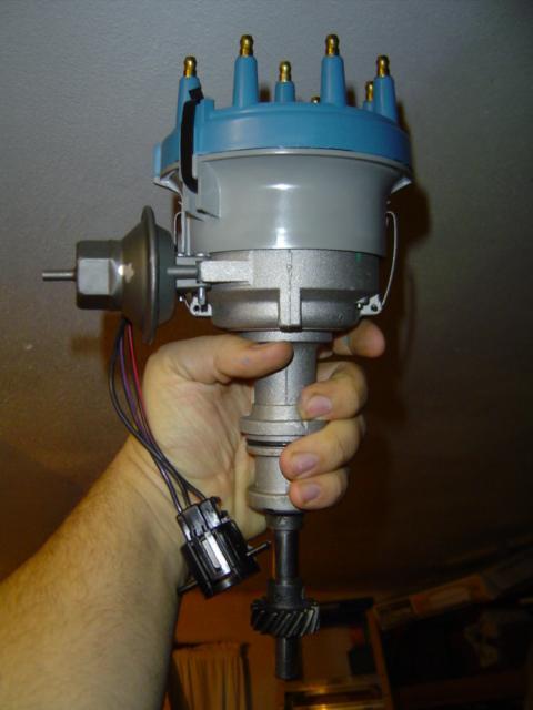 1979 Ford Bronco - A hand holds a car distributor, a key component of the ignition system.