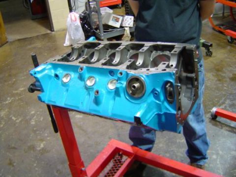 1979 Ford Bronco - Engine block painted blue sits on a red engine stand in a workshop.