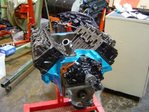 1979 Ford Bronco - Engine assembly on a stand, with a blue painted oil pan and black components visible.