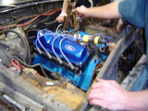 1979 Ford Bronco - Mechanics work on installing a blue Ford engine, new valve covers and spark plug wires.