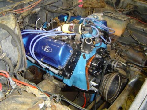 1979 Ford Bronco - Close-up of a blue Ford engine, likely undergoing a rebuild, with visible wiring and engine components.