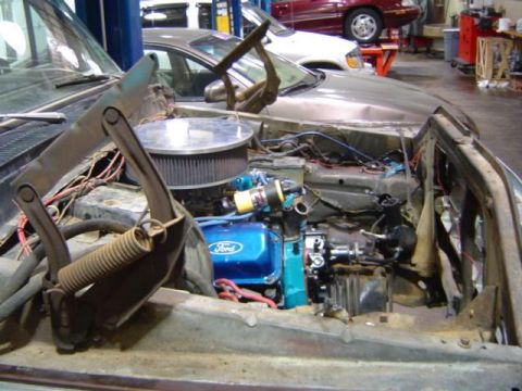 1979 Ford Bronco - The engine bay of a vehicle is shown with a blue Ford engine and exposed wiring.