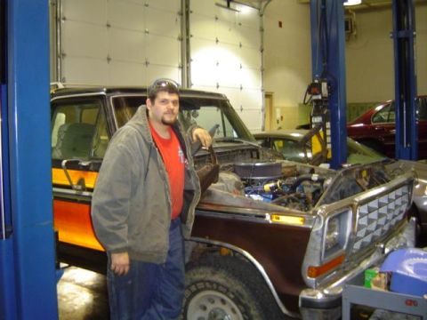 1979 Ford Bronco - A man stands by a pickup truck in a garage, with the engine exposed for work.