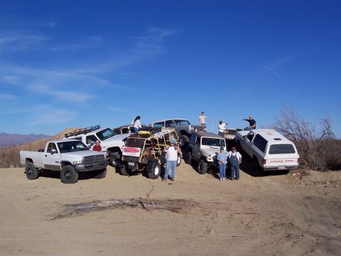 1981 Ford F-150 - A group of people and their off-road vehicles gathered on a sunny day in a desert landscape.