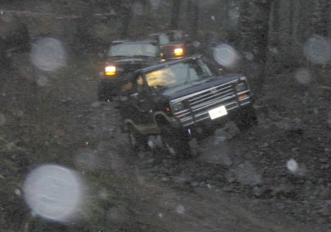 1991 Ford Explorer - Several SUVs navigate a challenging, wet, and muddy off-road path.