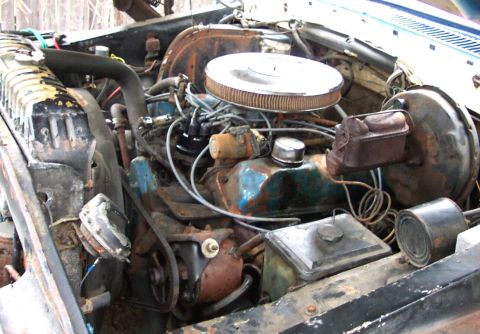 1975 Ford F-150 - The engine bay of a vehicle shows a V8 engine with various components and signs of wear.