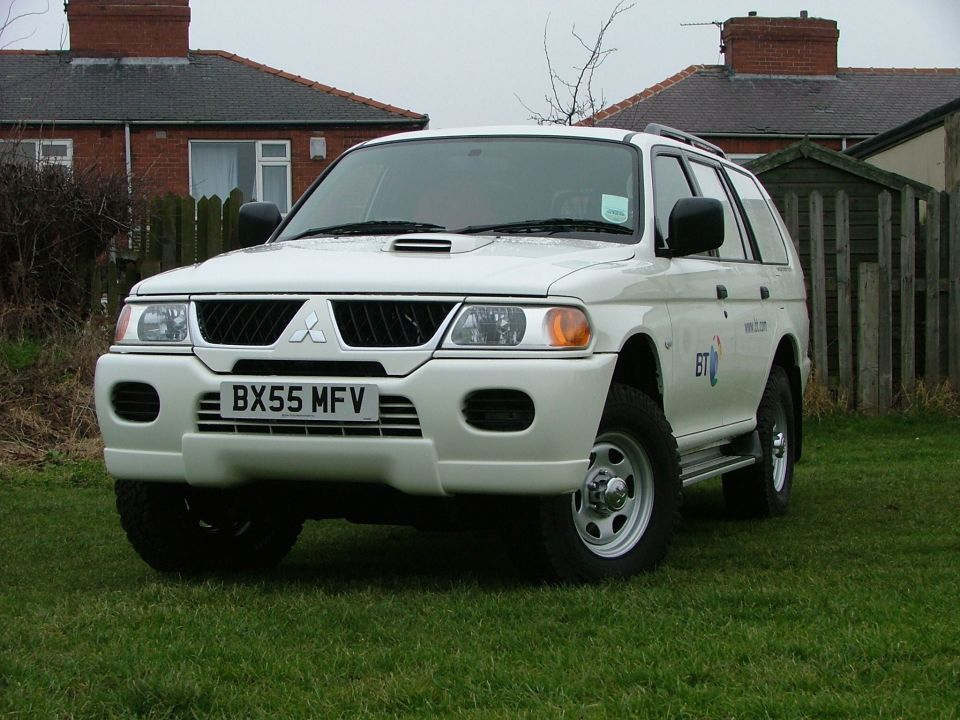 White Mitsubishi SUV with BT logo, front 3/4 view on grass, plate BX55 MFV