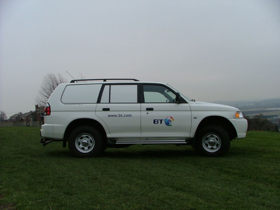 White Mitsubishi Shogun Sport 4x4 in BT fleet livery, side view on grass