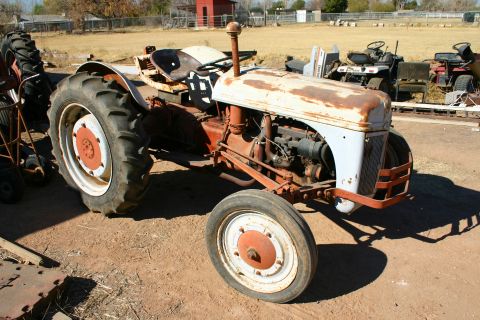 1981 Ford F-150 - This old tractor is parked outside with other farm equipment in the background.