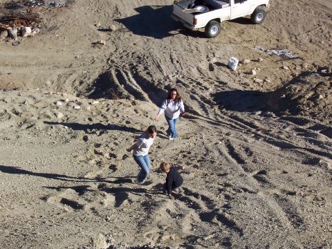 1981 Ford F-150 - A white 1981 Ford F-150 pickup truck is parked on a dirt embankment while people walk below.