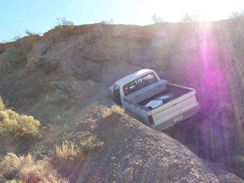 1981 Ford F-150 - A white pickup truck navigates a steep, rocky incline under a bright, sunny sky.