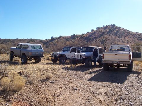 1981 Ford F-150 - Several off-road vehicles are parked in a desert landscape under a clear blue sky.