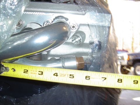 1986 Ford Bronco - Close-up of an engine part with a measuring tape, with another vehicle in the background.