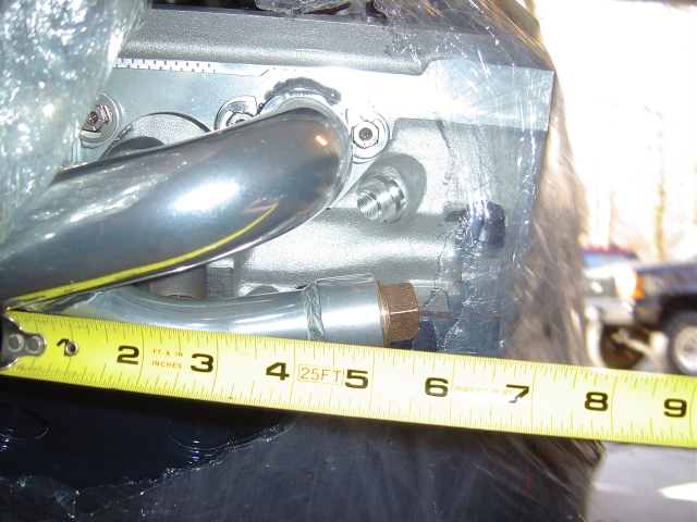 Chrome tube and brass fitting on engine part with tape measure for scale