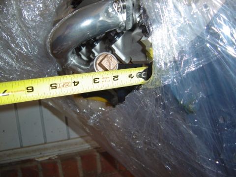1986 Ford Bronco - Measuring an engine part wrapped in plastic. The tape shows approximately 3 inches.