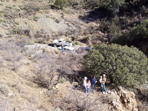 1981 Ford F-150 - A white 1979 Ford F-150 pickup truck is visible on a dirt road, with a group of people gathered on a hillside.