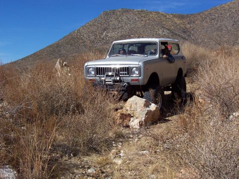1981 Ford F-150 - Silver International Scout II navigates a rocky, arid terrain with a winch mounted on the front bumper.