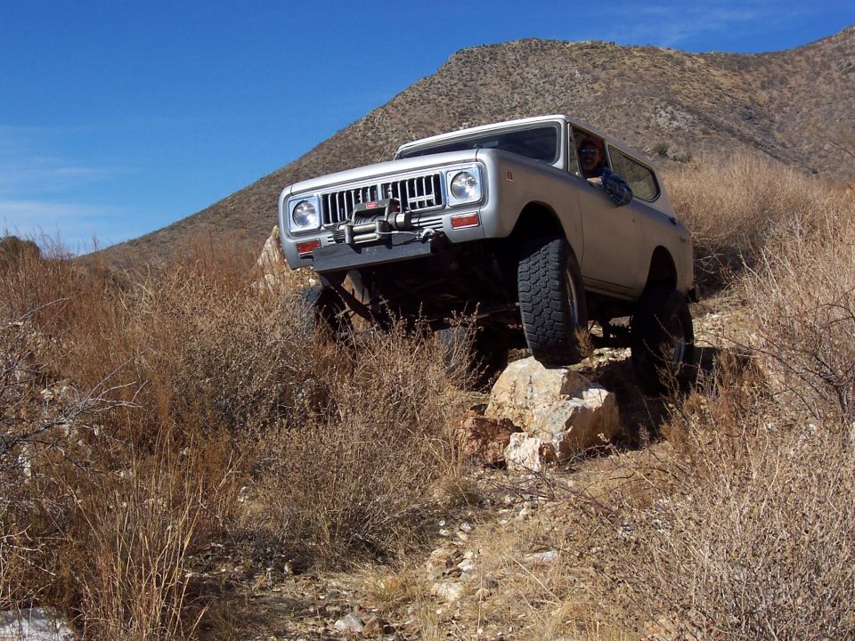 Silver International Scout II climbing over rocks on a dry, hilly trail