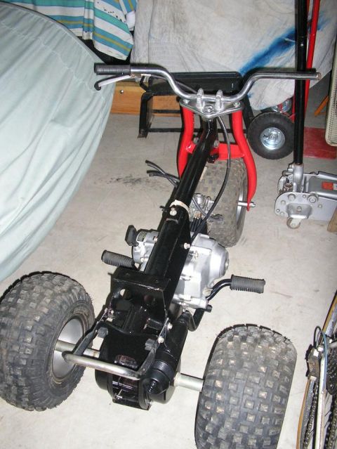 1900 Honda Big Red - This three-wheeled ATV is in a garage, possibly undergoing maintenance or storage.