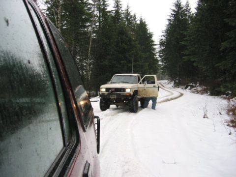 1991 Ford Explorer - Two SUVs on a snowy forest road, one with its door open.