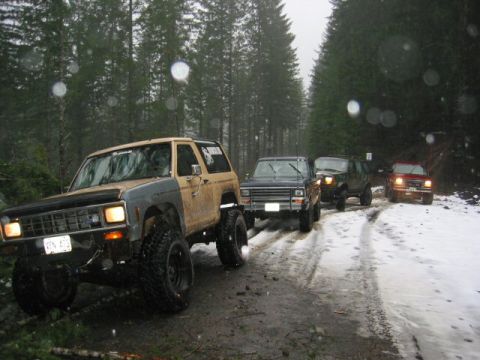 1991 Ford Explorer - A convoy of off-road vehicles, including a Ford Bronco II, navigates a snowy forest road.