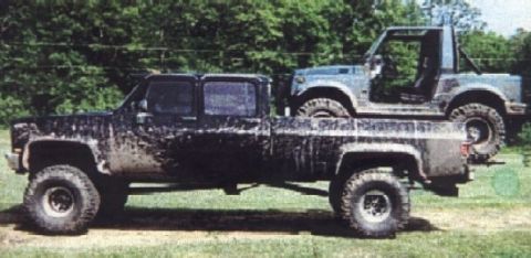 1977 Ford F-150 - A large black pickup truck, possibly from the late 1970s, is seen hauling a smaller, open-top SUV in its bed.