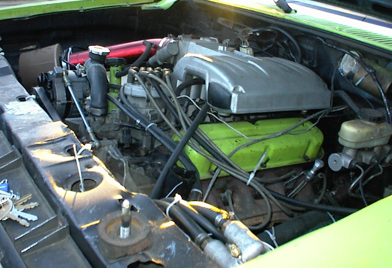 Engine bay with green valve covers and silver intake manifold. Keys on fender