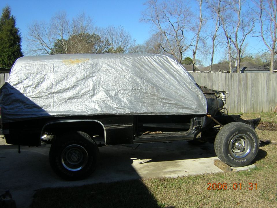 Truck cab covered with a silver tarp on a frame in a backyard, dated 2006.01.31