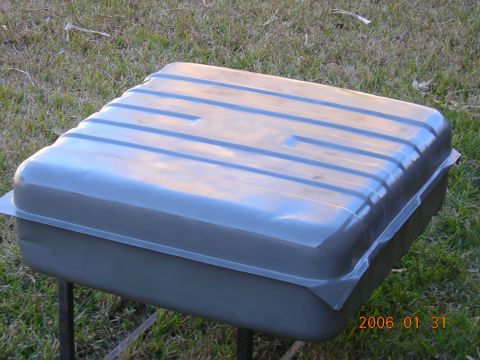 1986 Chevrolet Blazer - A gray metal fuel tank with horizontal ridges sits on metal legs on a grassy surface.