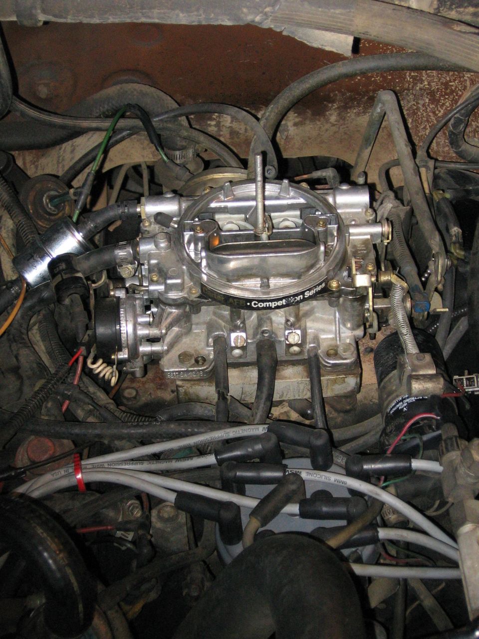 Edelbrock Competition Series carburetor on engine intake with spark plug wires and hoses