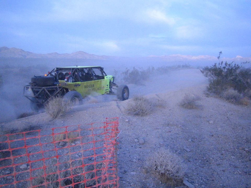 Green Weger Mortgage off-road buggy on desert ridge trail at dusk