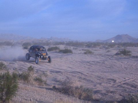 Off-road buggy number 517 on sandy desert with mountains in the distance