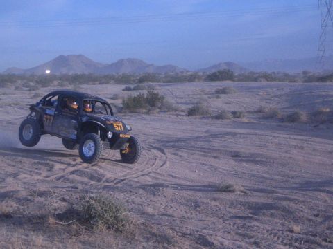 Off-road buggy number 577 with two occupants on sandy desert course