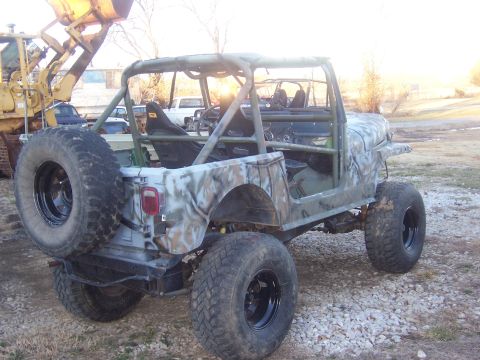 1992 Ford C-250 (Centurion Conversions) - This modified Jeep CJ features a camouflage paint scheme and an external roll cage, with a bulldozer in the background.