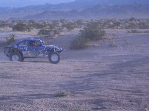 Blue and white off-road racing Baja Bug numbered 552 driving across desert flats