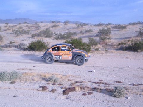 Orange and black BFGoodrich off-road racing Beetle number 1148 on desert track