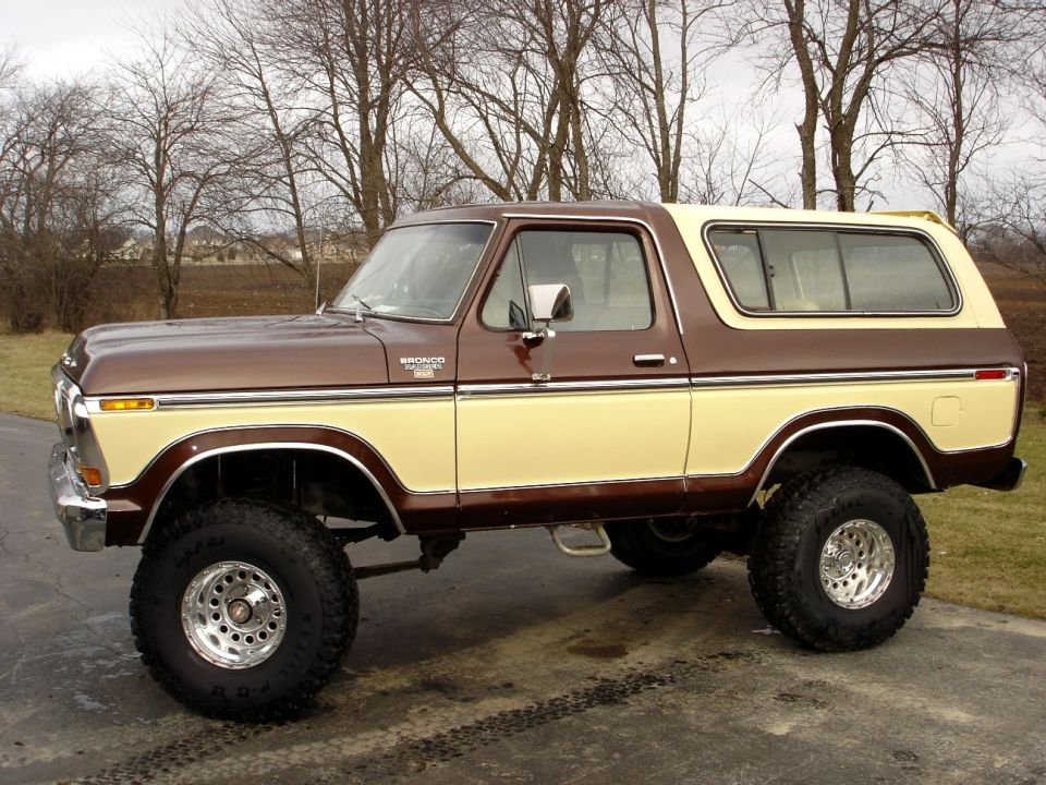 Brown and tan two-tone late-1970s Ford Bronco lifted with chrome wheels