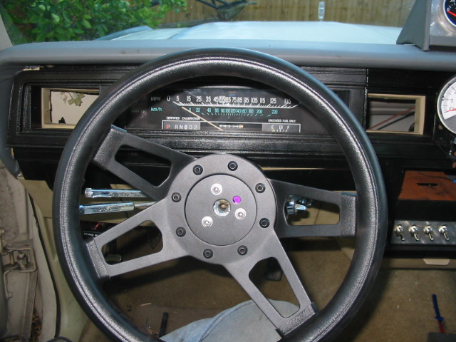 Aftermarket steering wheel in a car interior, showing the dashboard and gauges